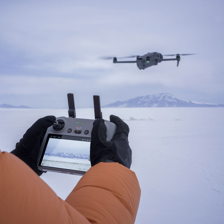 DJI Mavic 4 Pro flying over snow with DJI RC 2 in the foreground